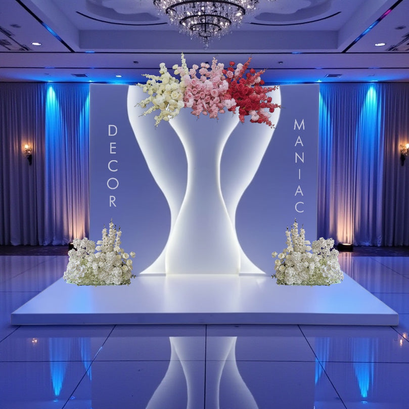 Decorative setup with large white backdrop holding flowers on a stage, with 'Decor Maniacs' branding.